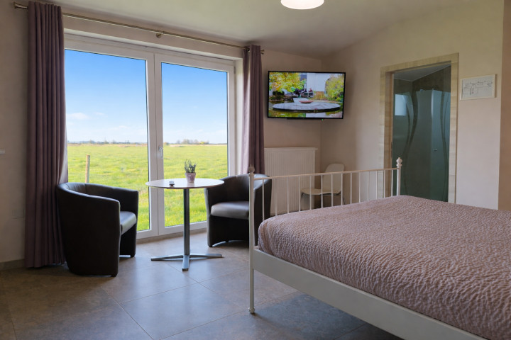 ruime kamer met groot raam en uitzicht op de polderweiden